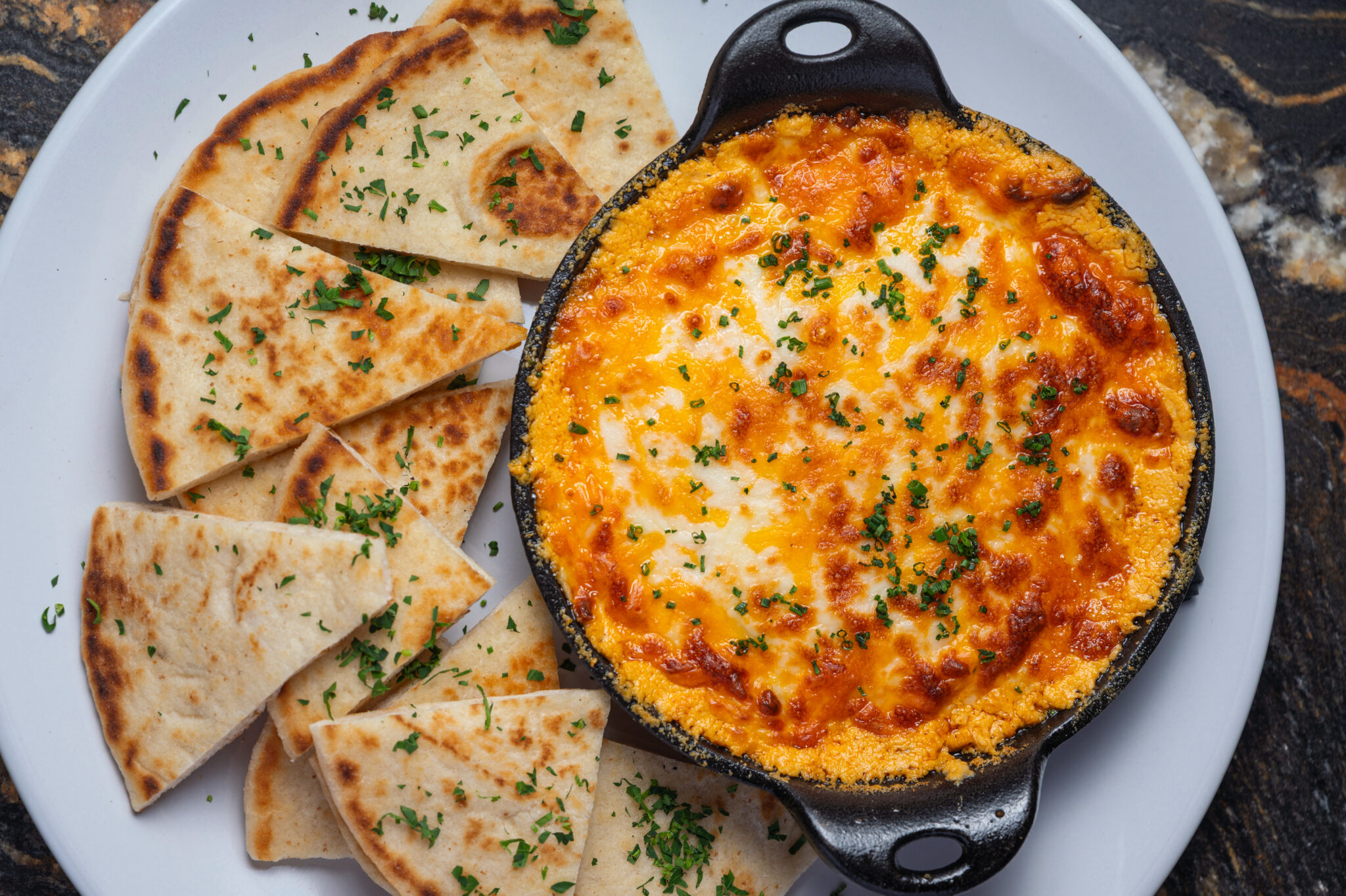 Baked cheese dip bubbling in a cast iron skillet with warm grilled flatbread