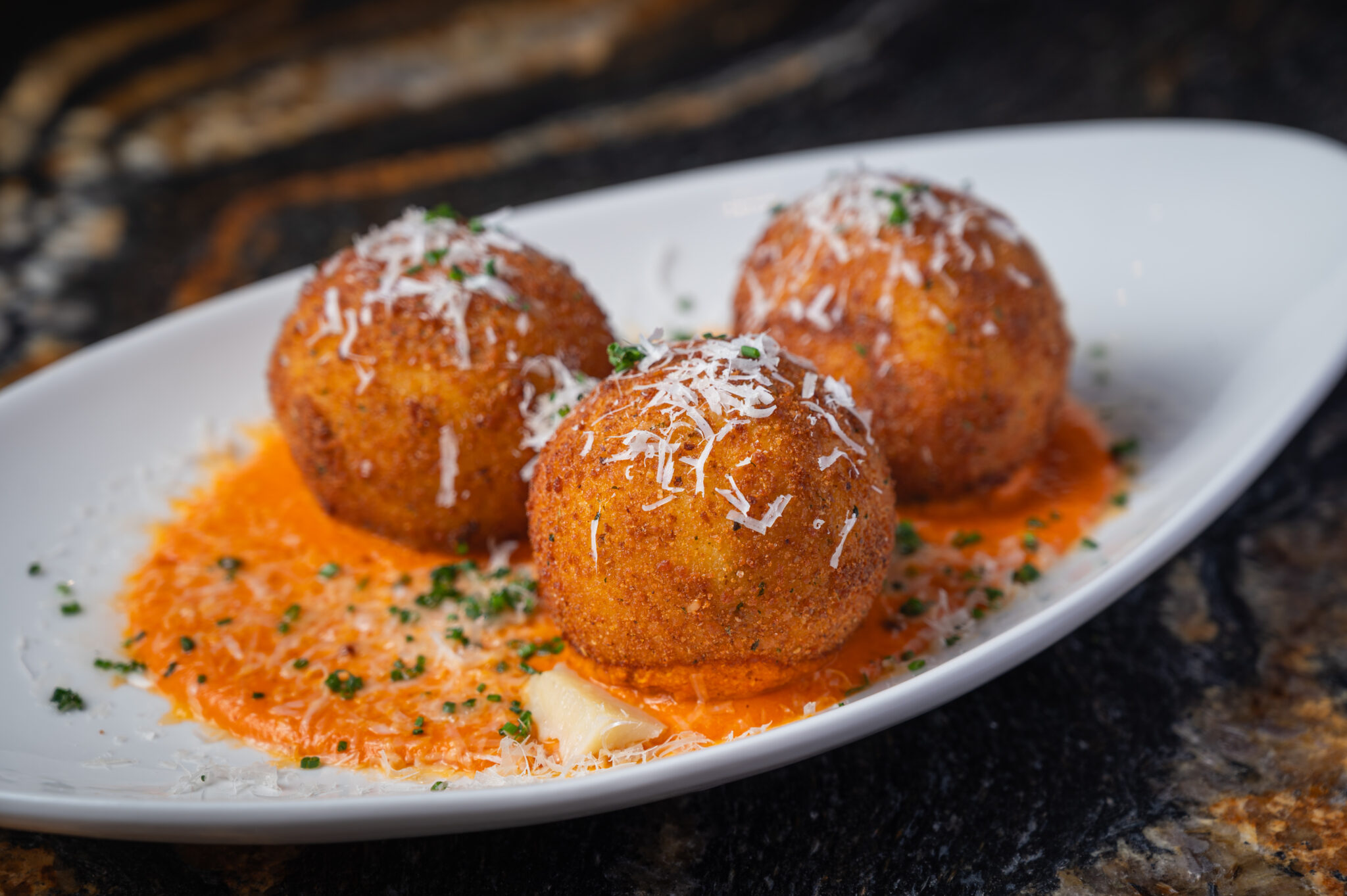 Crispy fried arancini over vodka sauce, finished with shaved parmesan and chives