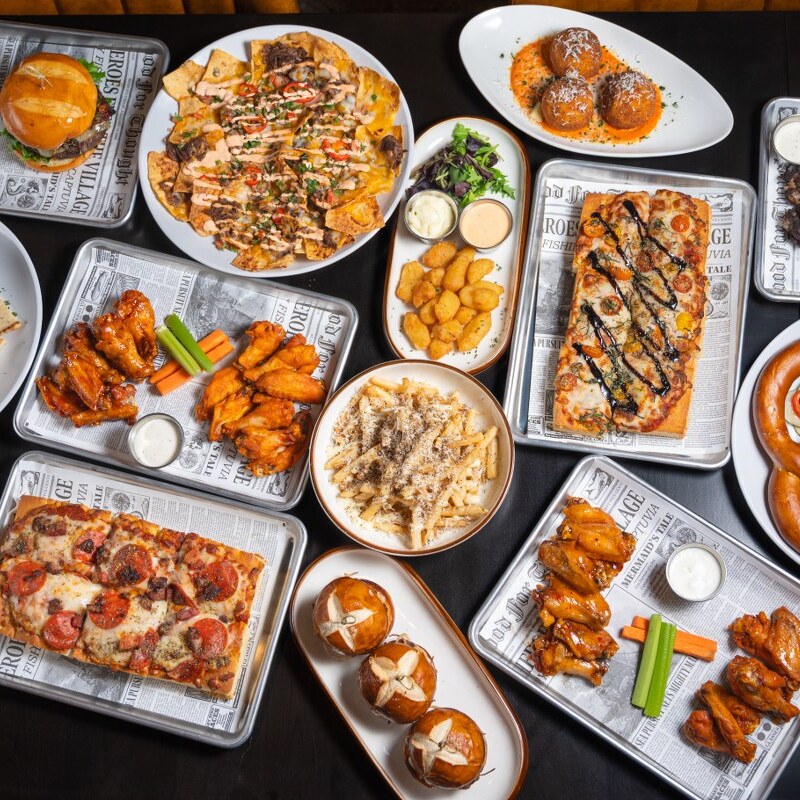 An overhead spread of the Bridewell Tavern menu with wings, nachos, Tuscan pizzas, sliders, arancini and truffle fries